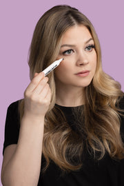 A model using makeup remover pen to touch up makeup.