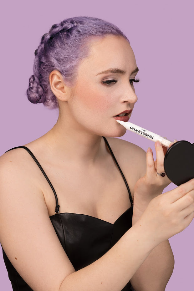 A model using a makeup remover pen with micellar water to touch up her lipstick.